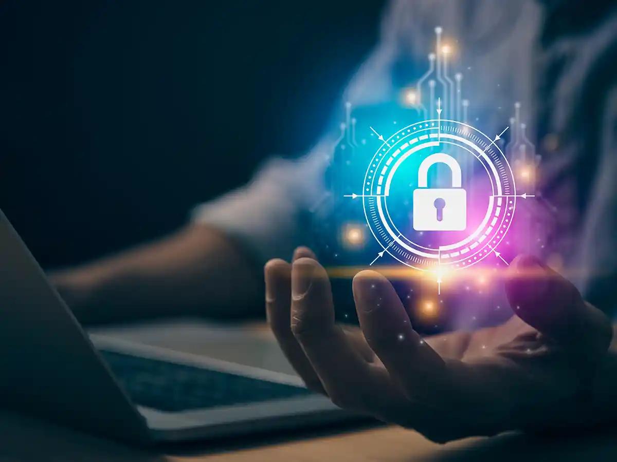 A cybersecurity expert at his computer holding an illuminated image of a lock